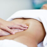 Hands massaging female abdomen.Therapist applying pressure on belly. Woman receiving massage at spa salon