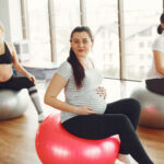 Pregnant women in a gym. Girls diong yoga. Women working together.